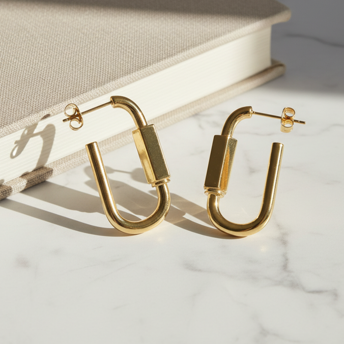 Gold hoop earrings on a marble surface with a book in the background
