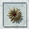 Gold brooch with a central gemstone on a marble surface