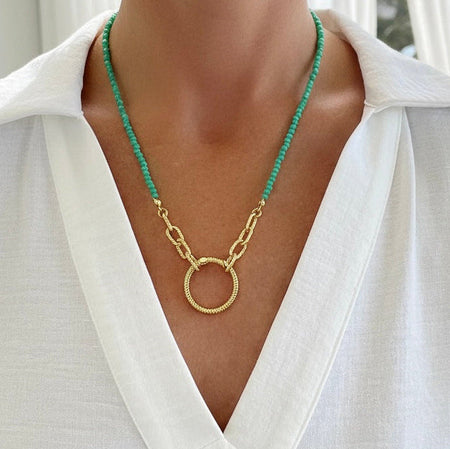Green beaded necklace with a gold chain on a white shirt