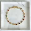 Gold bracelet with colorful gemstones on a marble surface
