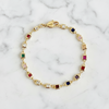 Gold bracelet with colorful gemstones on a marble background