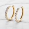 Gold hoop earrings with clear gemstones on a light gray background