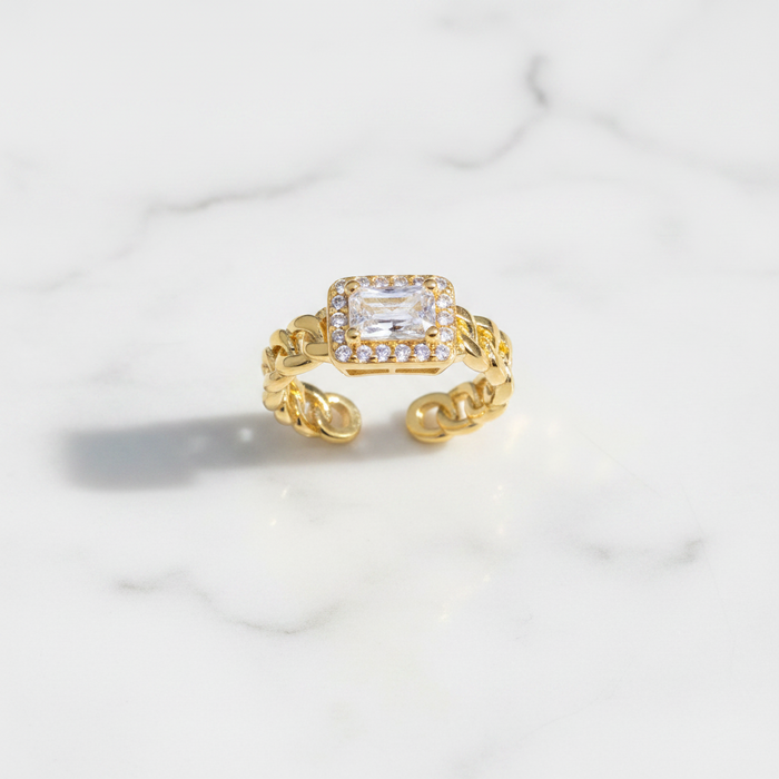 Gold ring with a diamond on a marble surface
