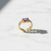 Gold ring with a purple gemstone on a white background