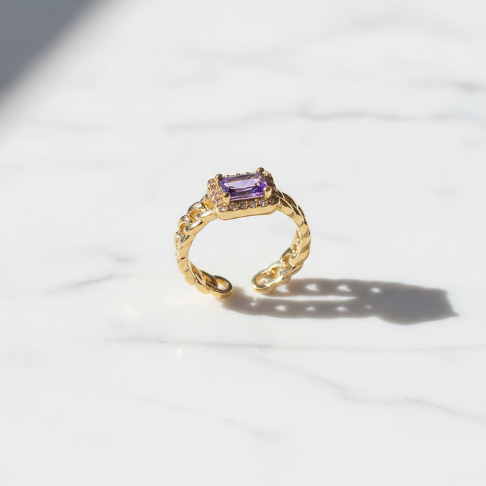 Gold ring with a purple gemstone on a white background