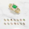 Gold ring with a green gemstone and smaller gemstone rings on a white background