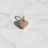 Gold heart-shaped pendant with clear stones on a marble background