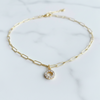 Gold chain necklace with a small round pendant on a light background