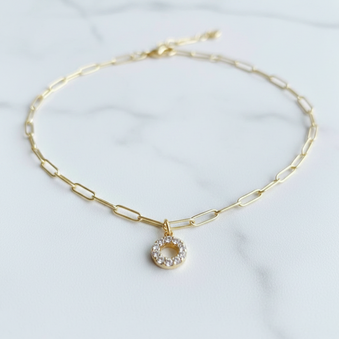 Gold chain necklace with a small round pendant on a light background