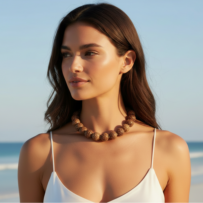 Woman wearing a white top and brown necklace on a beach