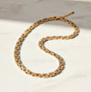 Gold necklace with clear stones on a light background