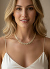 Woman wearing a gold necklace against a neutral background
