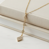 Gold necklace with diamond pendants on a beige surface
