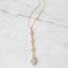 Gold necklace with diamond-like beads on a marble surface