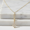 Gold necklace with a diamond pendant on a marble surface