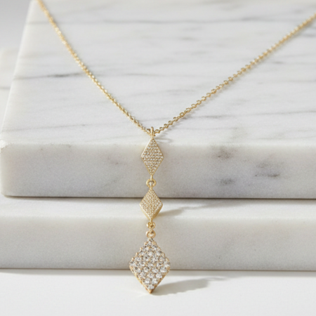 Gold necklace with a diamond pendant on a marble surface