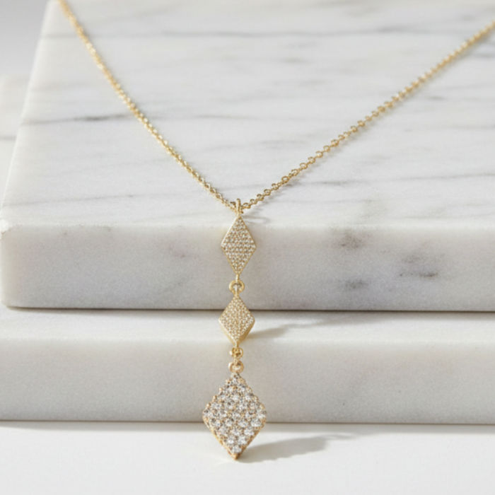 Gold necklace with a diamond pendant on a marble surface
