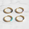 Four gold hoop rings with colored accents on a light background