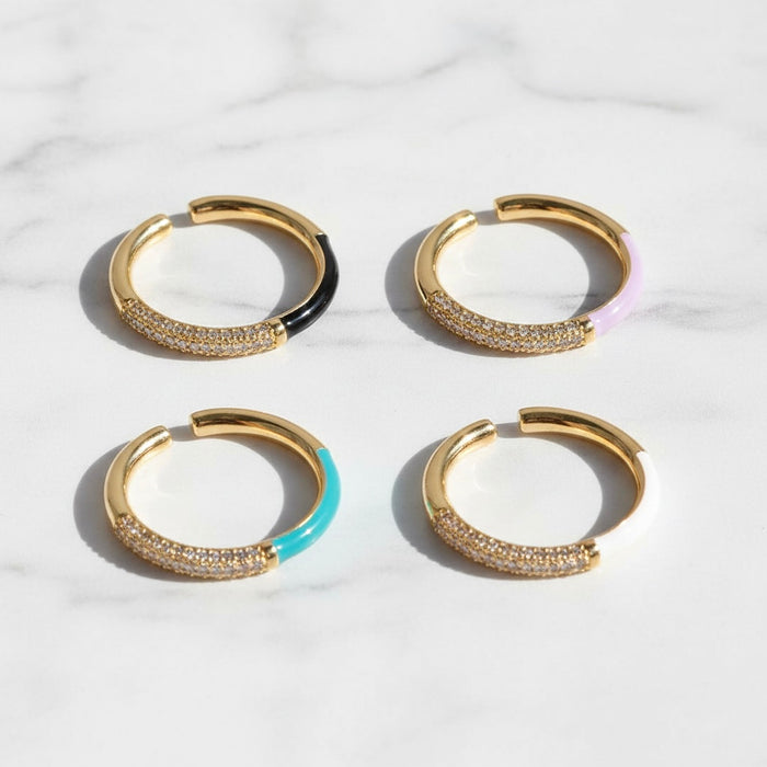 Four gold hoop rings with colored accents on a light background