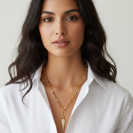 Woman wearing a gold necklace with a white shirt against a plain background