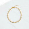 Gold anklet with small pearls on a white background