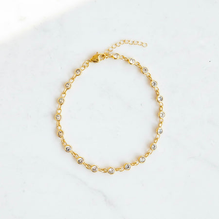 Gold anklet with small pearls on a white background