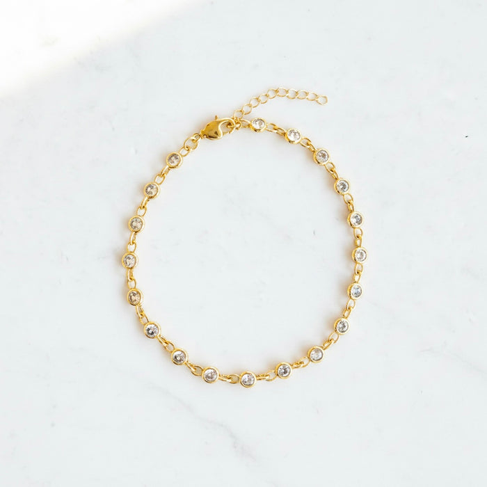 Gold anklet with small pearls on a white background