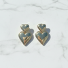 Heart-shaped gold earrings on a light marble background