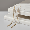 Gold earrings with clear stones on a marble surface