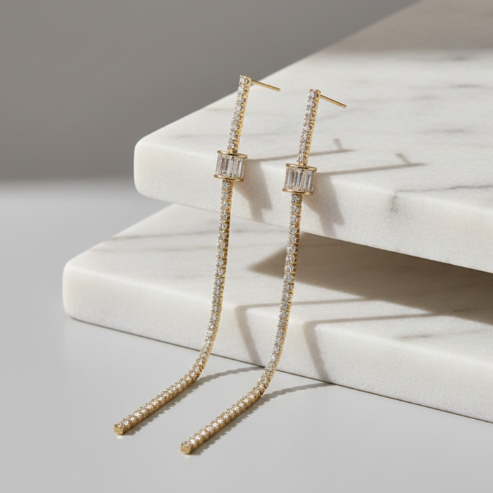 Gold earrings with clear stones on a marble surface