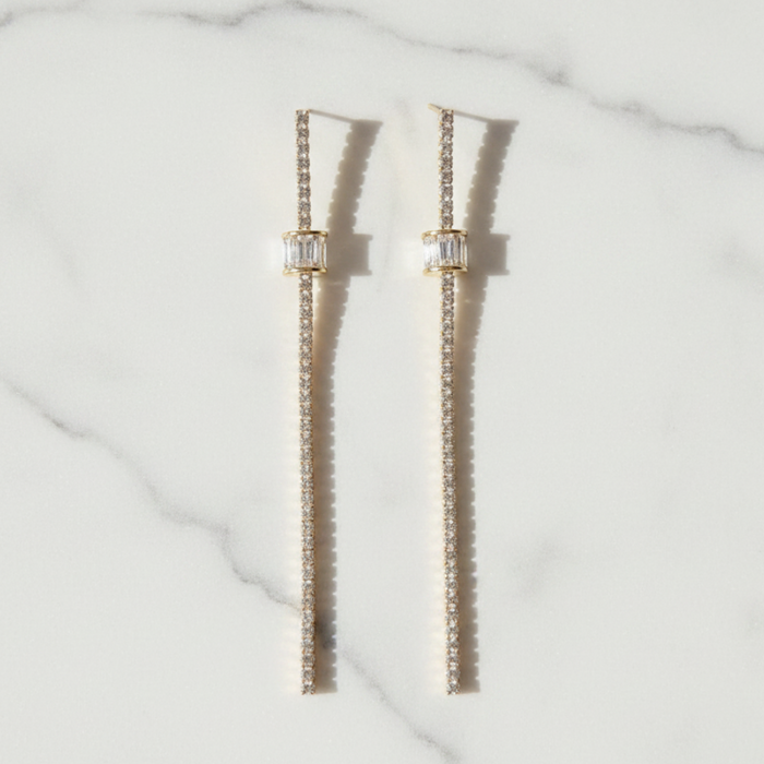 Pair of gold chain earrings on a marble surface