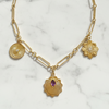 Gold necklace with three charms on a marble background
