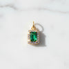 Gold pendant with a green gemstone on a white marble background