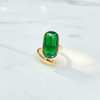 Gold ring with a green gemstone on a white background