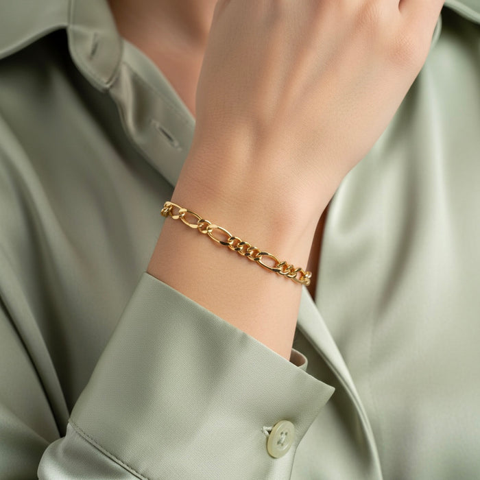 Gold chain bracelet on a person wearing a light green shirt