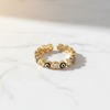 Gold ring with black and white gemstones on a light background