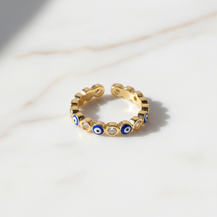Gold ring with blue and white eye designs on a light background