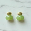 Pair of green earrings with gold tops on a marble surface