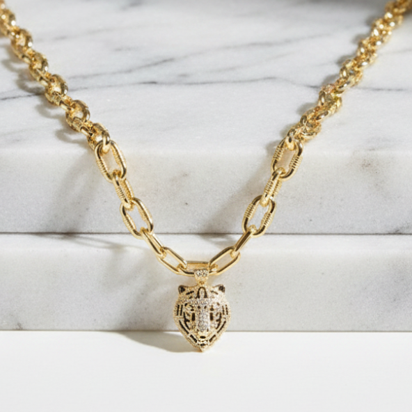 Gold chain necklace with a heart pendant on a marble surface