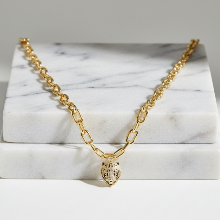 Gold chain necklace with a heart pendant on a marble surface