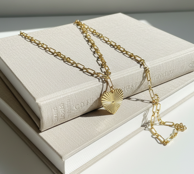 Gold necklace with a heart pendant on a stack of books