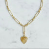 Gold necklace with a heart-shaped pendant on a marble background