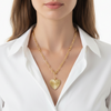 Gold chain necklace with a heart pendant worn by a person in a white shirt on a white background