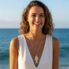 Woman wearing a necklace with a pendant against a blue ocean background
