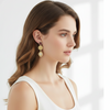 Woman wearing gold earrings with a plain background