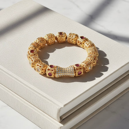 Gold bracelet with red stones on a white surface