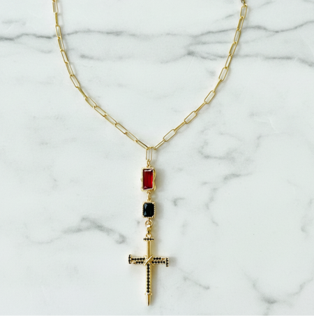 Gold necklace with a cross pendant on a marble background