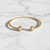 Gold bracelet and earrings on a marble surface