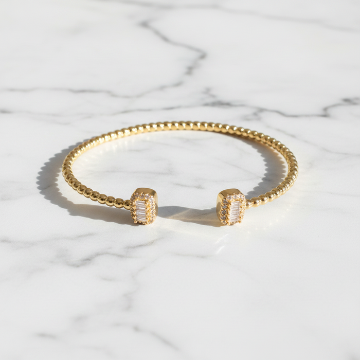 Gold bracelet and earrings on a marble surface