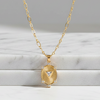 Gold necklace with a pendant on a marble surface